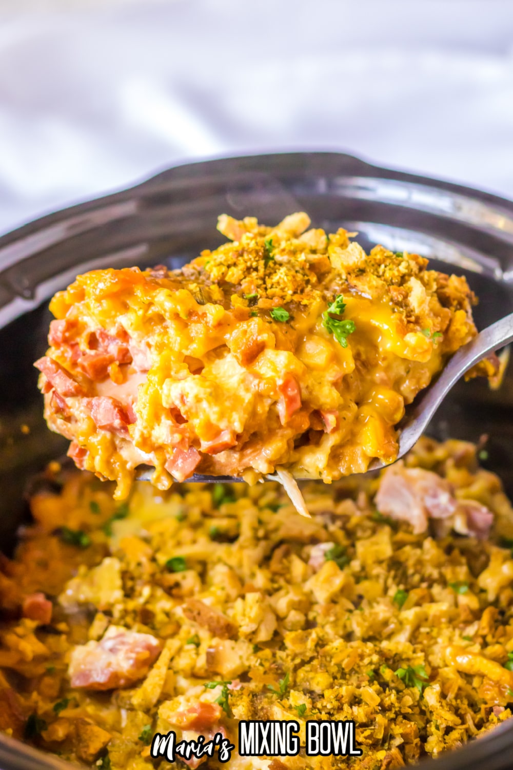 spoonful of chicken cordon bleu held in the air above a slow cooker