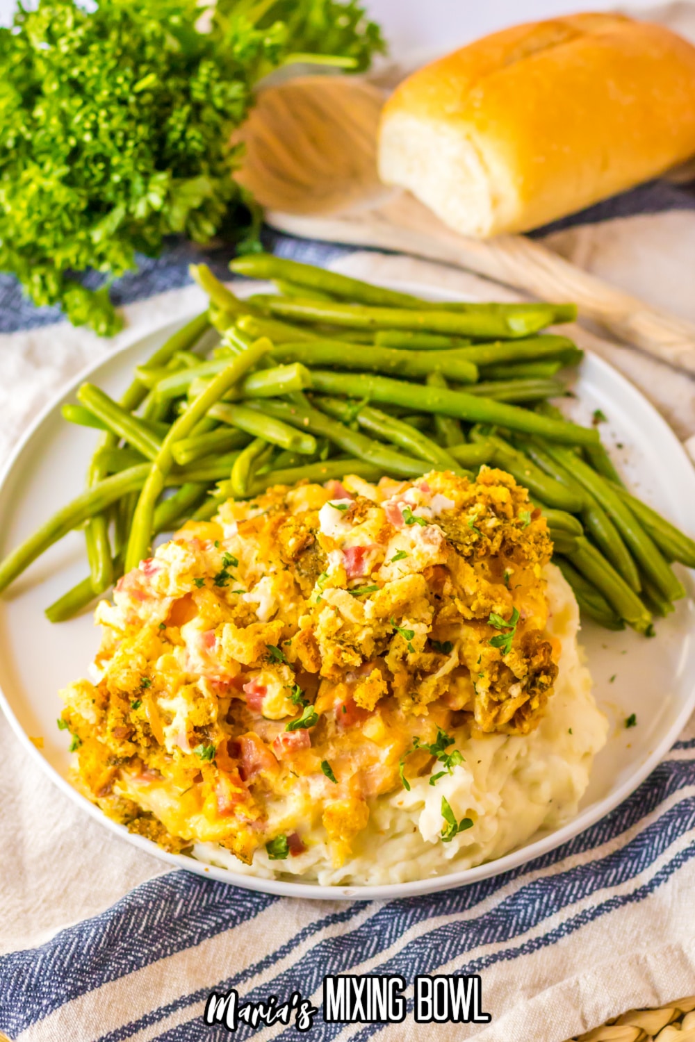 plate with chicken cordon bleu casserole on top of a bed of mashed potatoes with a side of fresh green beans