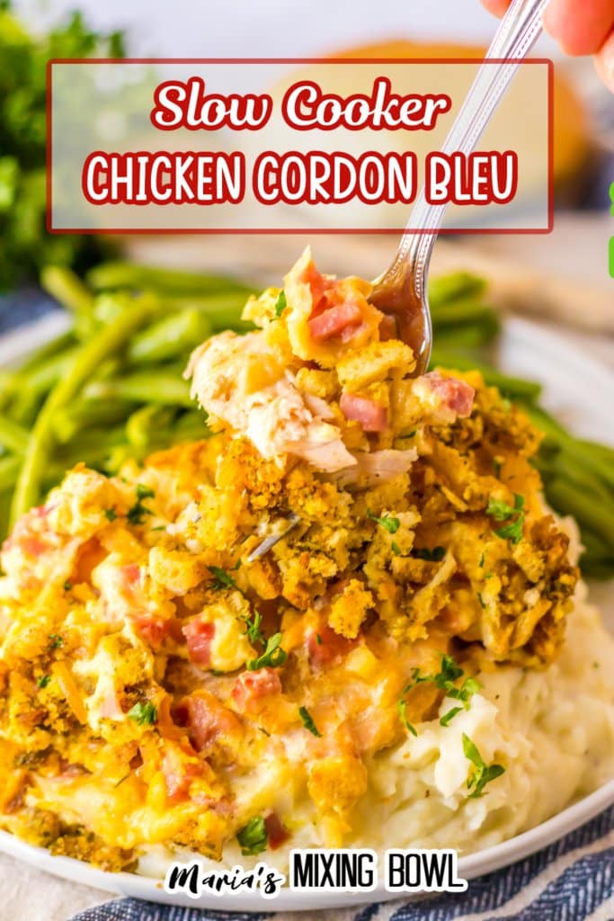 fork full of chicken cordon bleu on a plate with mashed potatoes and green beans