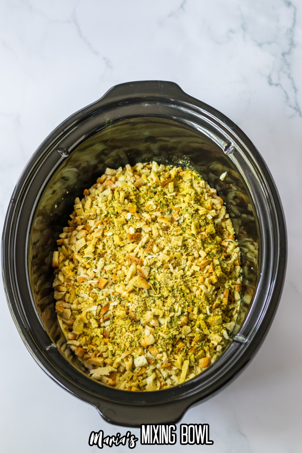 raw chicken breasts topped with sauce and stuffing in a slow cooker
