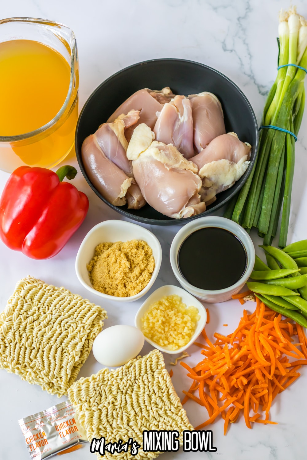 bowls of broth, raw chicken thighs, green onions, bell pepper, soy sauce, ginger, garlic, egg, ramen noodles, matchstick carrots, and snow peas