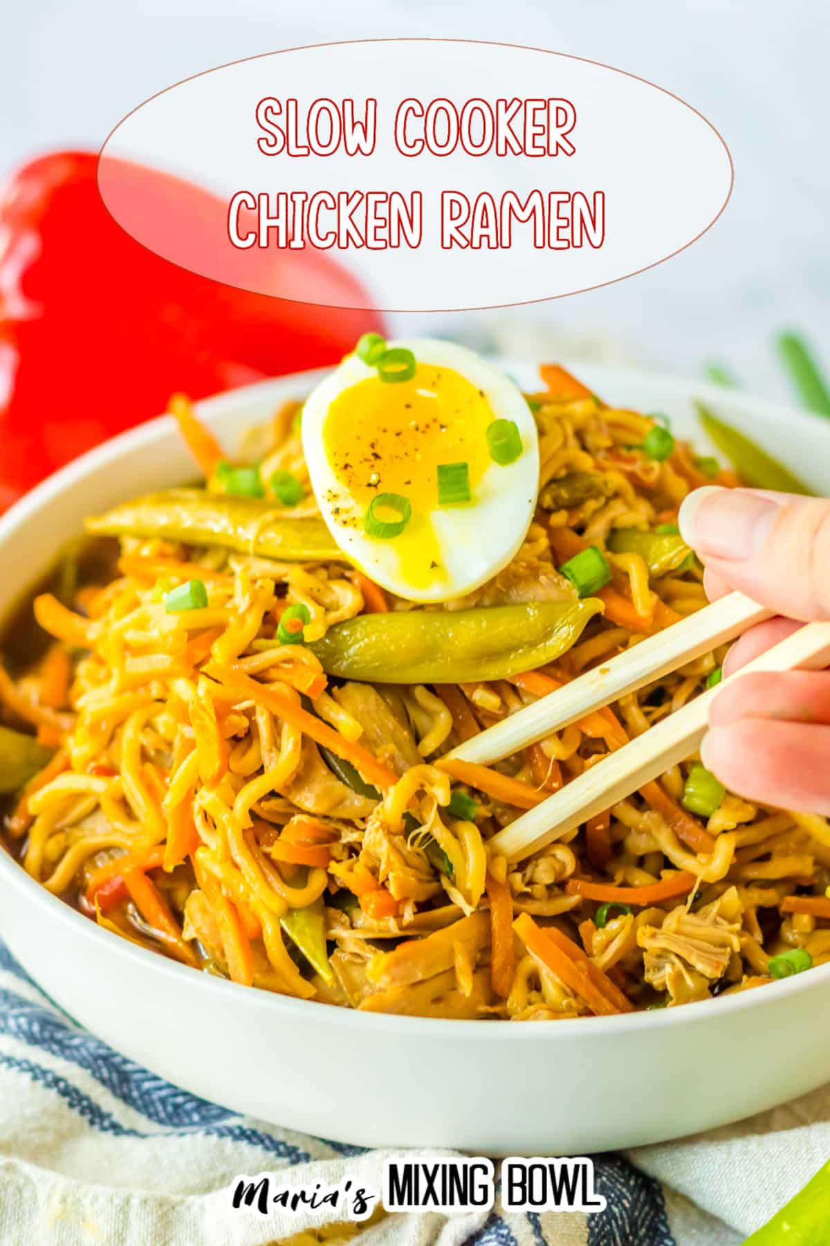 close up of a bowl of chicken ramen with a bite being removed with chopsticks