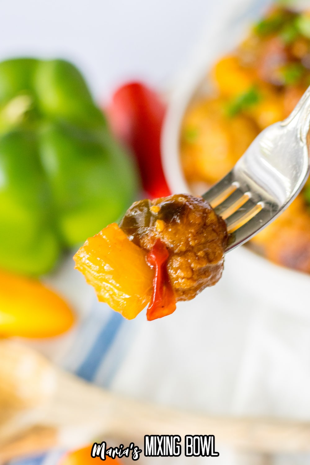 meatball, pepper and piece of pineapple held on a fork in the air