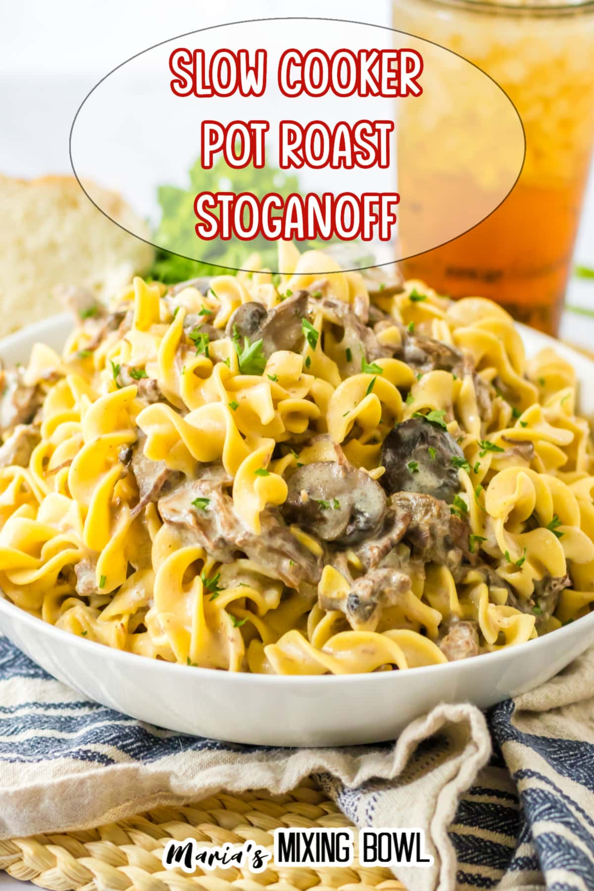 white bowl filled with slow cooker pot roast stroganoff with a glass of iced tea in the background