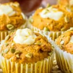 four pumpkin muffins filled with cream cheese filling in the center on a table.