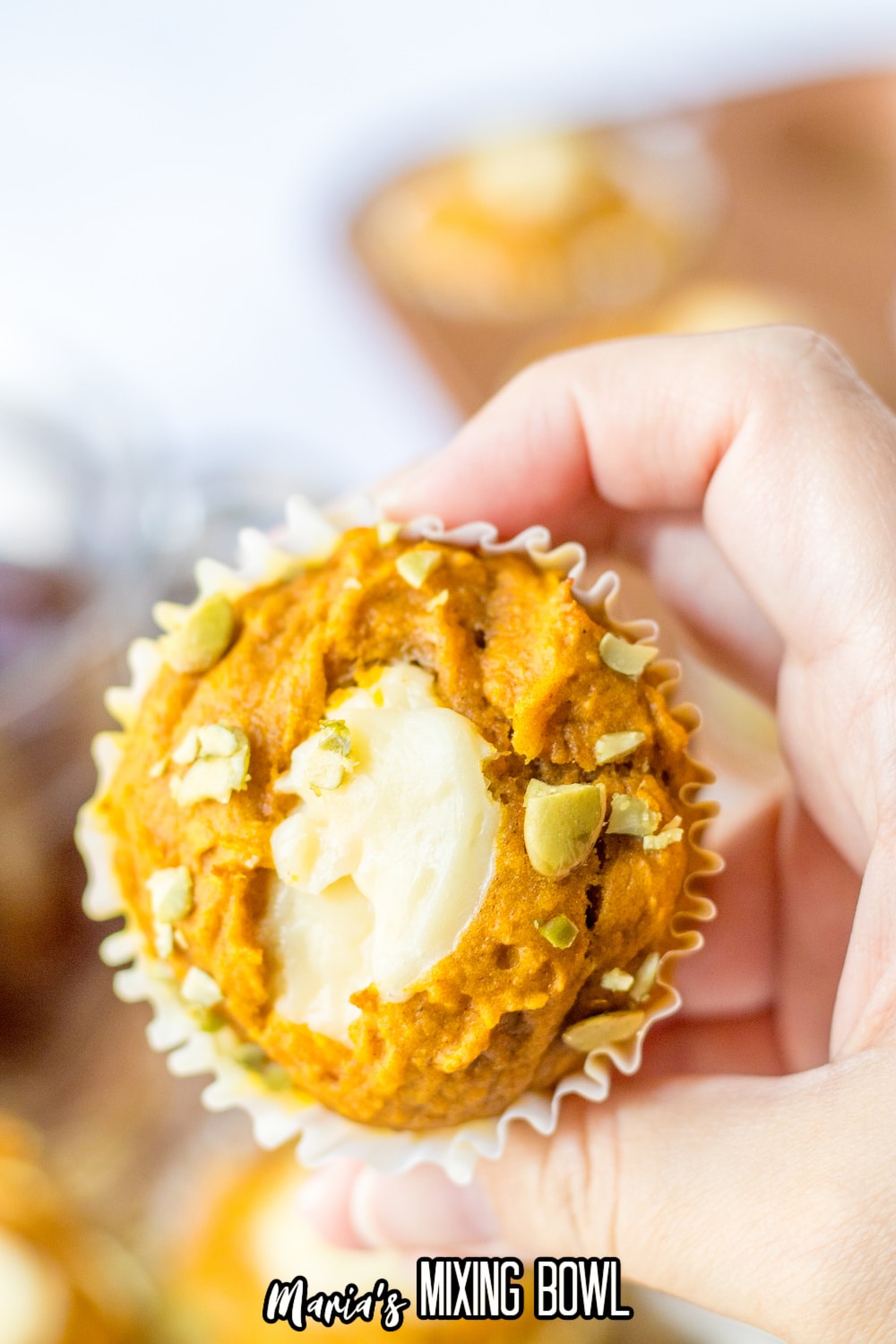 pumpkin muffin with cream cheese center held in a woman's hand.
