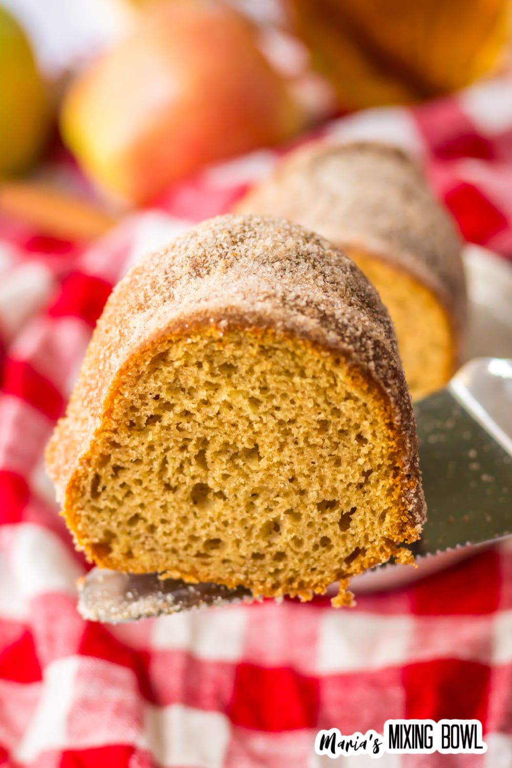 slice of apple cider donut cake held on a spatula in the air.