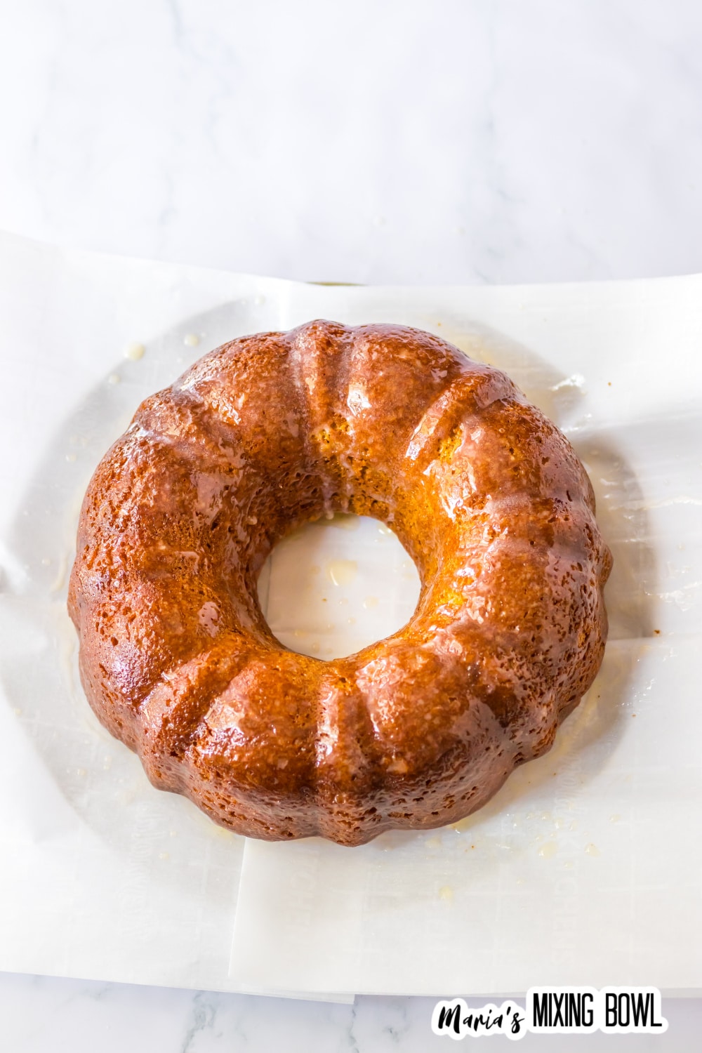melted butter being brushed on top of a baked bundt cake.