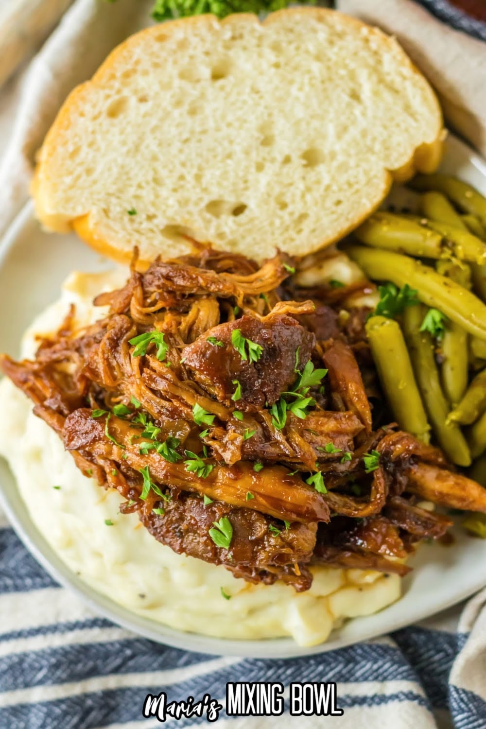 shredded pork loin on top of a bed of mashed potatoes on a plate.