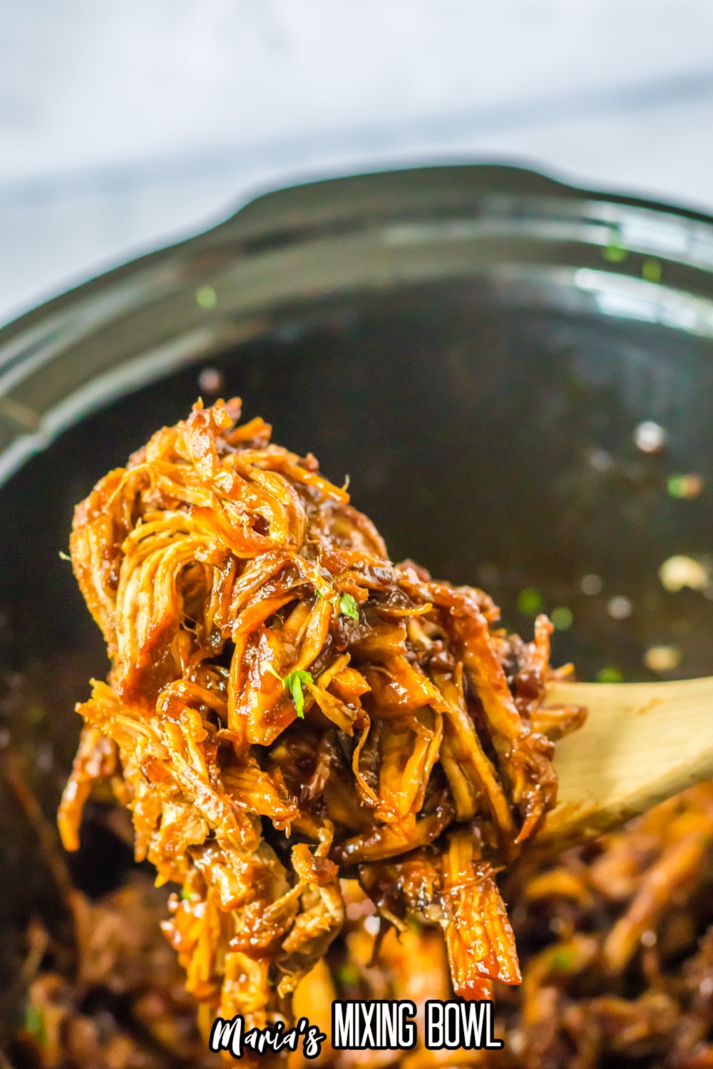 wooden spoon of shredded pork loin held in the air.