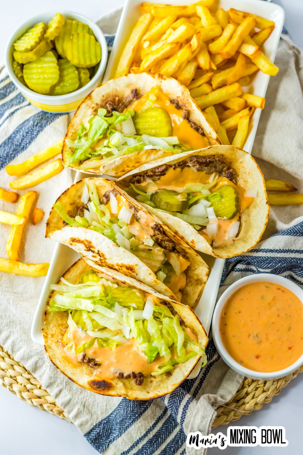 four big mac tacos and a side of fries on a white platter.