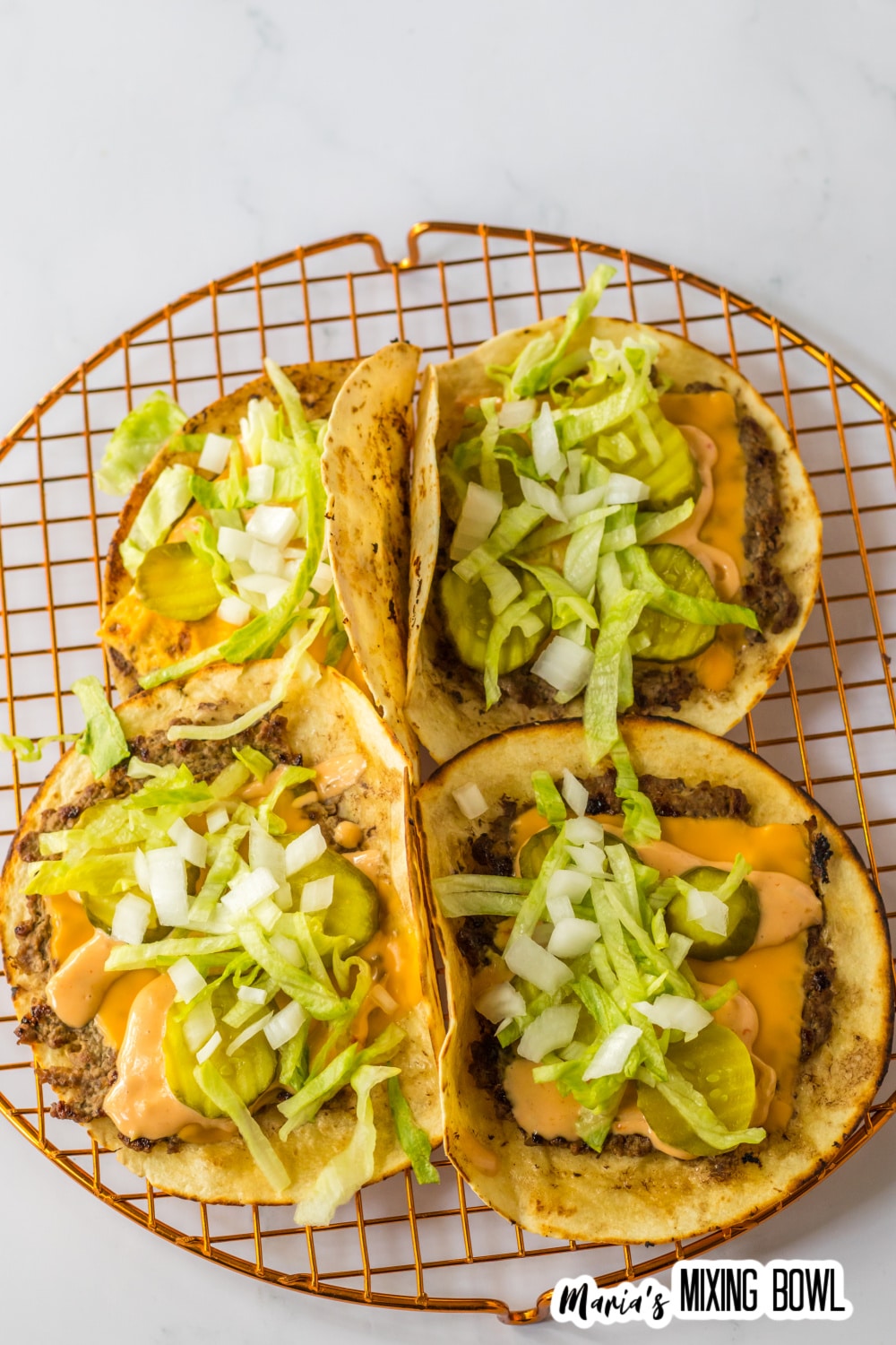 lettuce and pickles being topped on the big mac tacos.