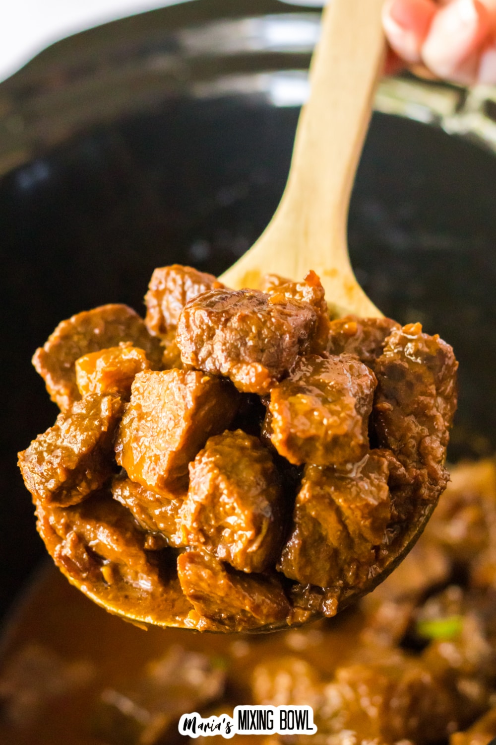 large wooden spoon full of honey bourbon steak bites held in the air.