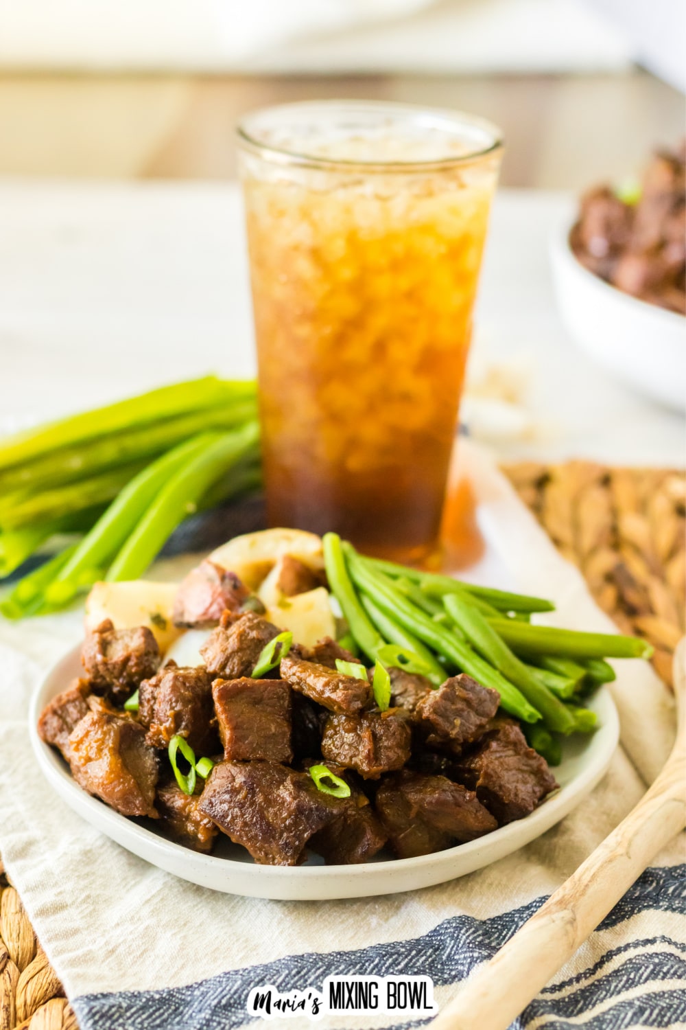 white plate filled with bourbon steak bites, cooked potatoes, and green beans.