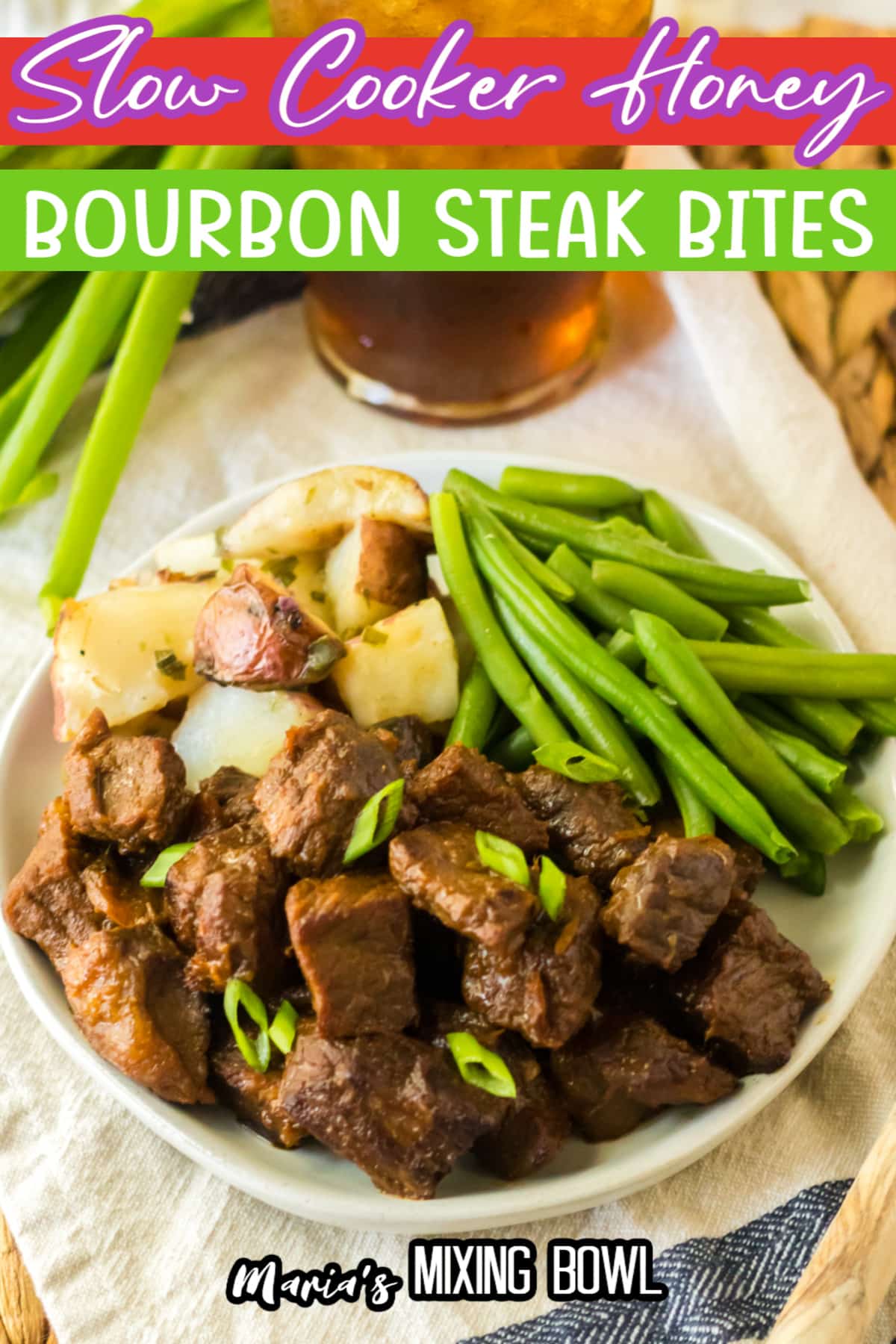 white plate filled with bourbon steak bites, cooked potatoes, and green beans.