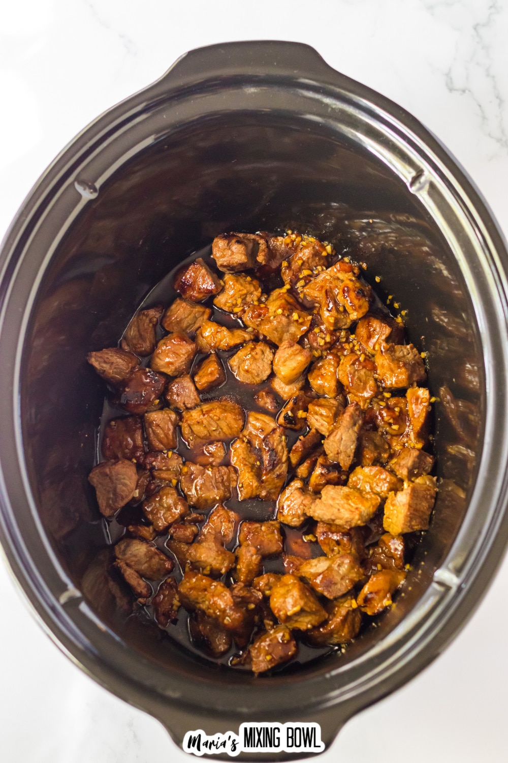 seared steak bites and honey bourbon sauce in the slow cooker ready to be cooked.