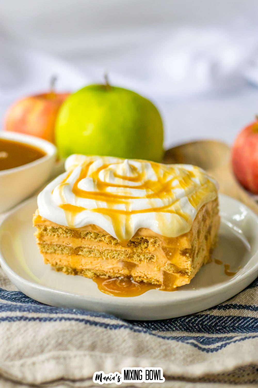 slice of caramel apple icebox cake on a white plate topped with caramel drizzle.