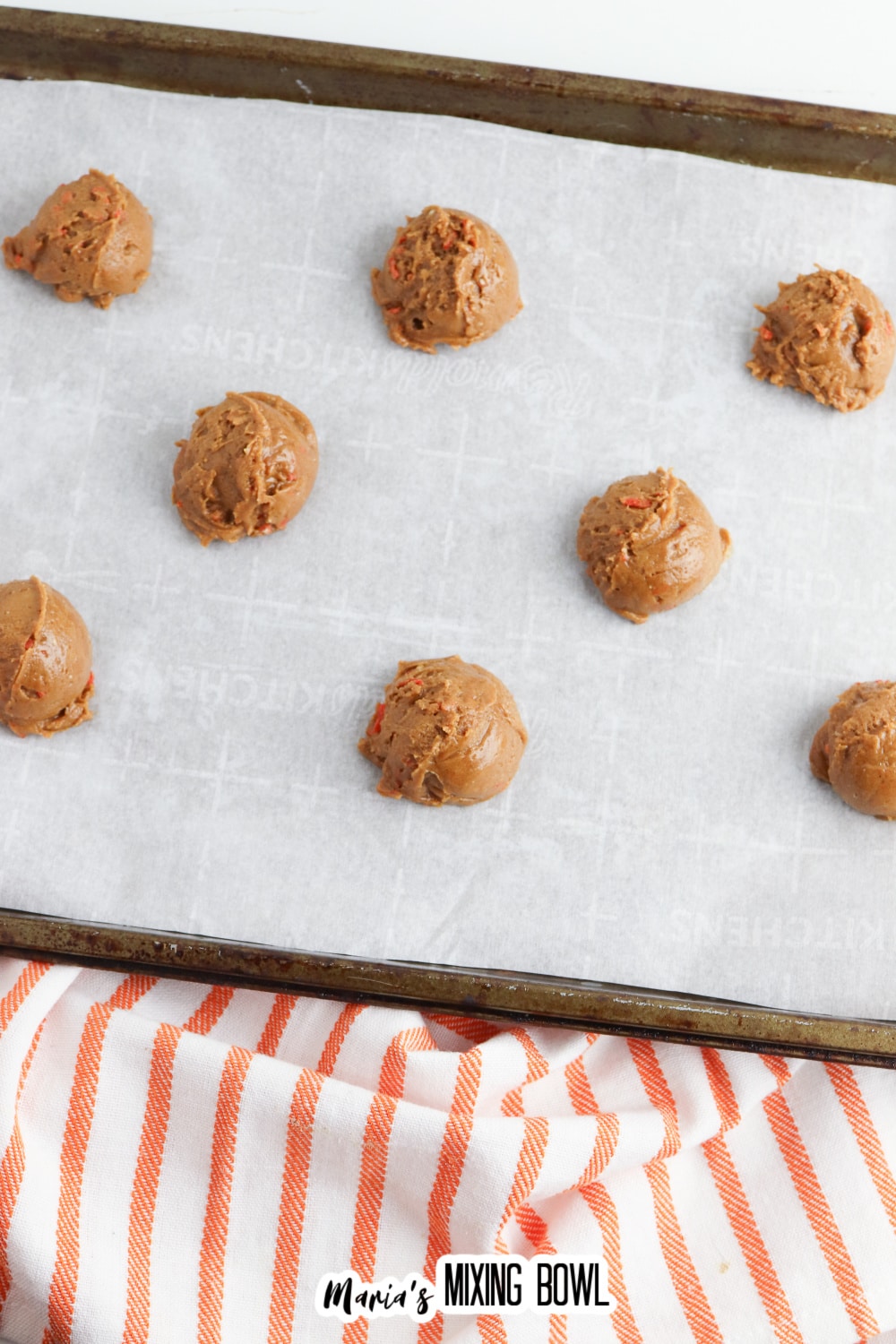 cookie dough balls on a parchment lined baking sheet.