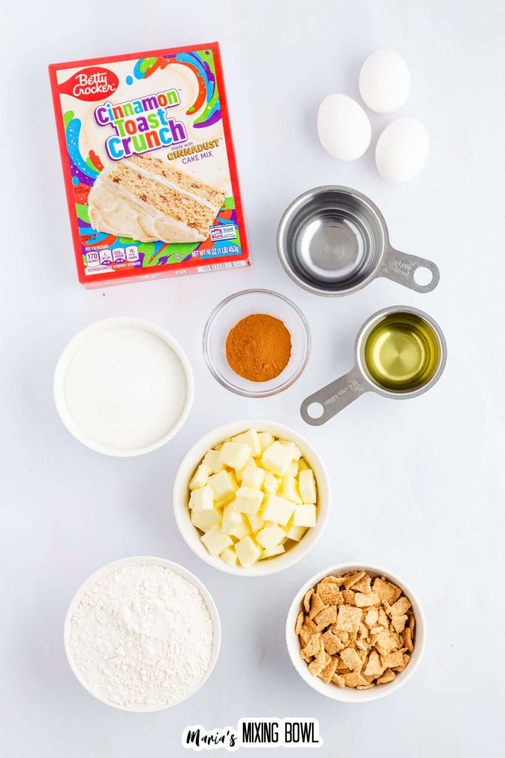 box of cinnamon toast crunch cake, bowls of oil, water, cinnamon, sugar, butter, powdered sugar, cinnamon toast crunch cereal and eggs.