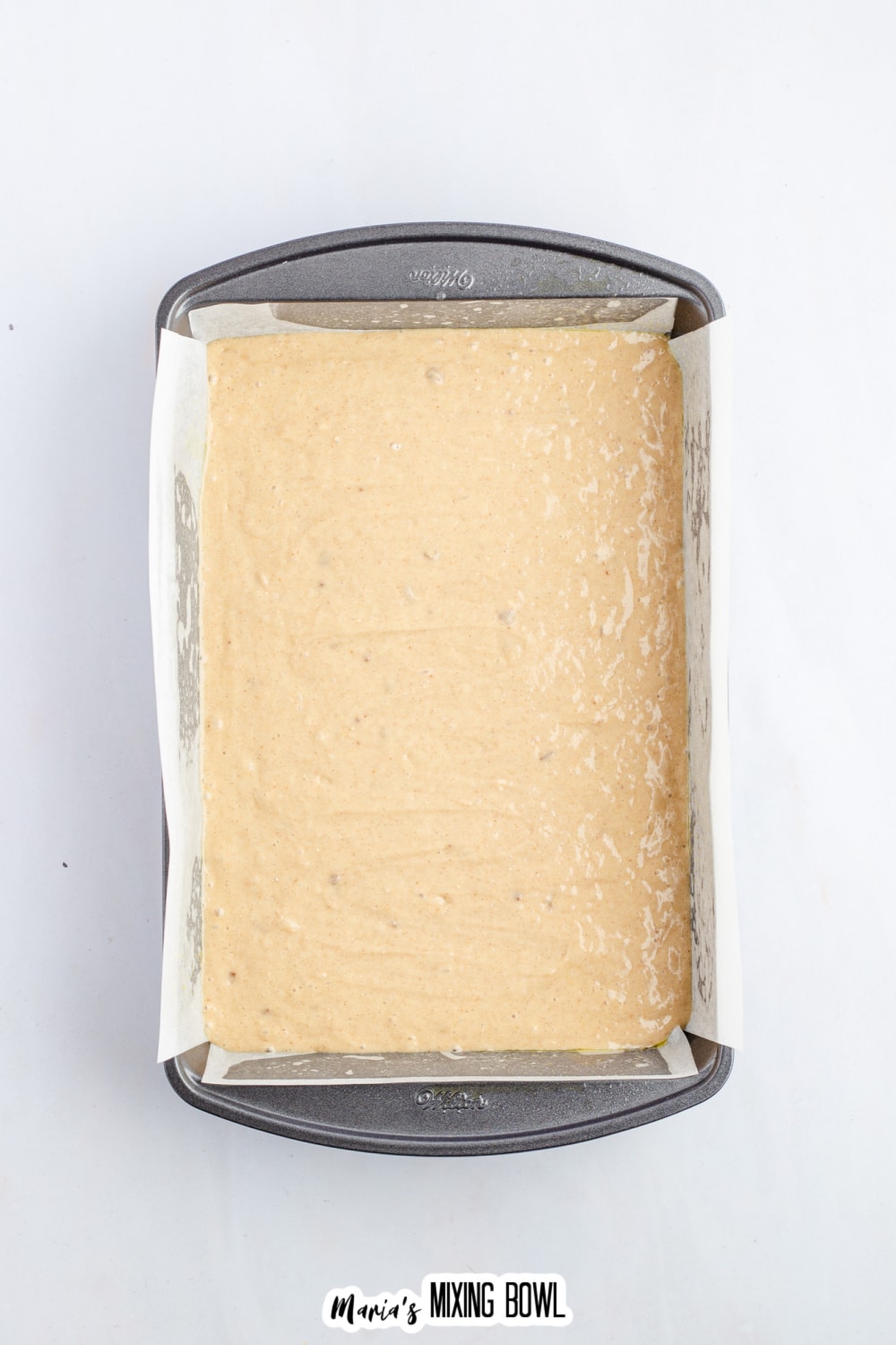 cake batter in a parchment lined baking dish ready for the oven.