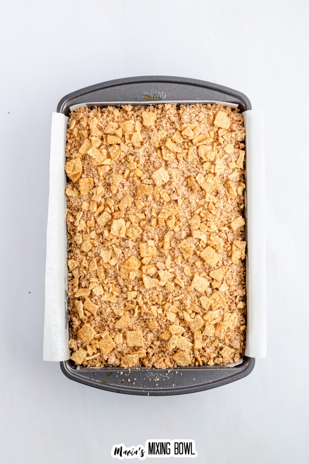 cinnamon toast crunch cake in a parchment lined baking dish.