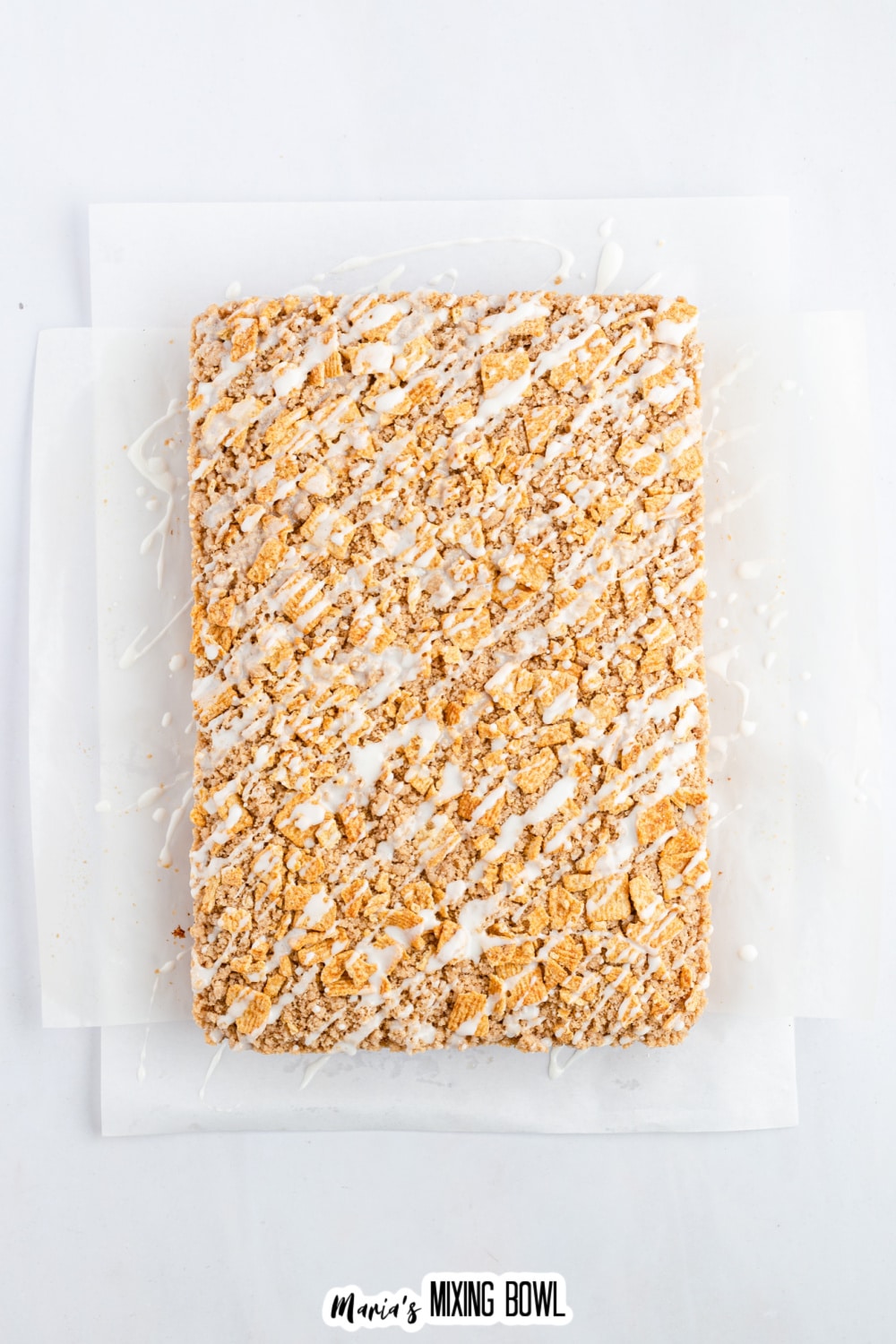 vanilla drizzled being poured on top of cinnamon toast crunch cake.
