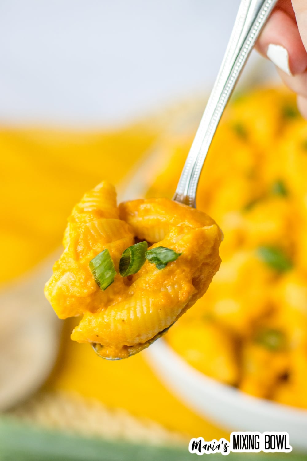 bite of creamy pumpkin mac and cheese on a spoon held in the air.