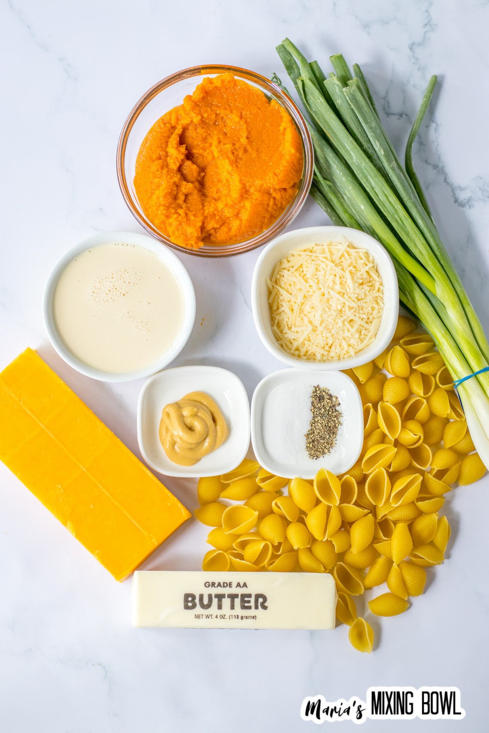 bowls of pumpkin puree, parmesan cheese, pasta shells, salt, pepper, mustard, cheddar cheese, butter, green onions, and heavy cream.