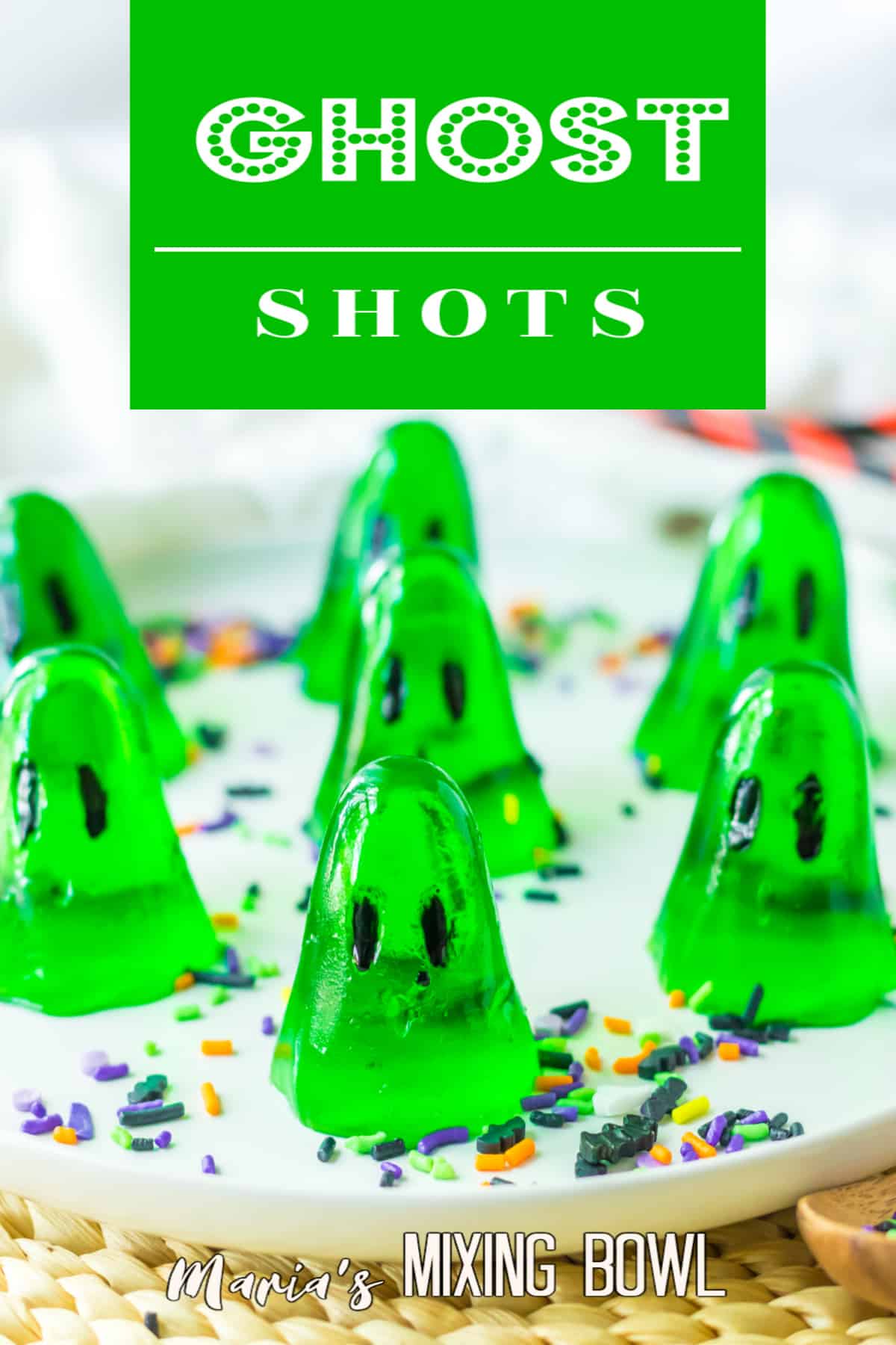 seven green gelatin ghosts on a white plate with sprinkles.