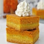 two gooey pumpkin bars stack on a plate.