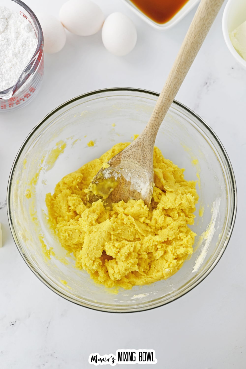 pumpkin bar dough being mixed in a glass bowl with a wooden spoon.