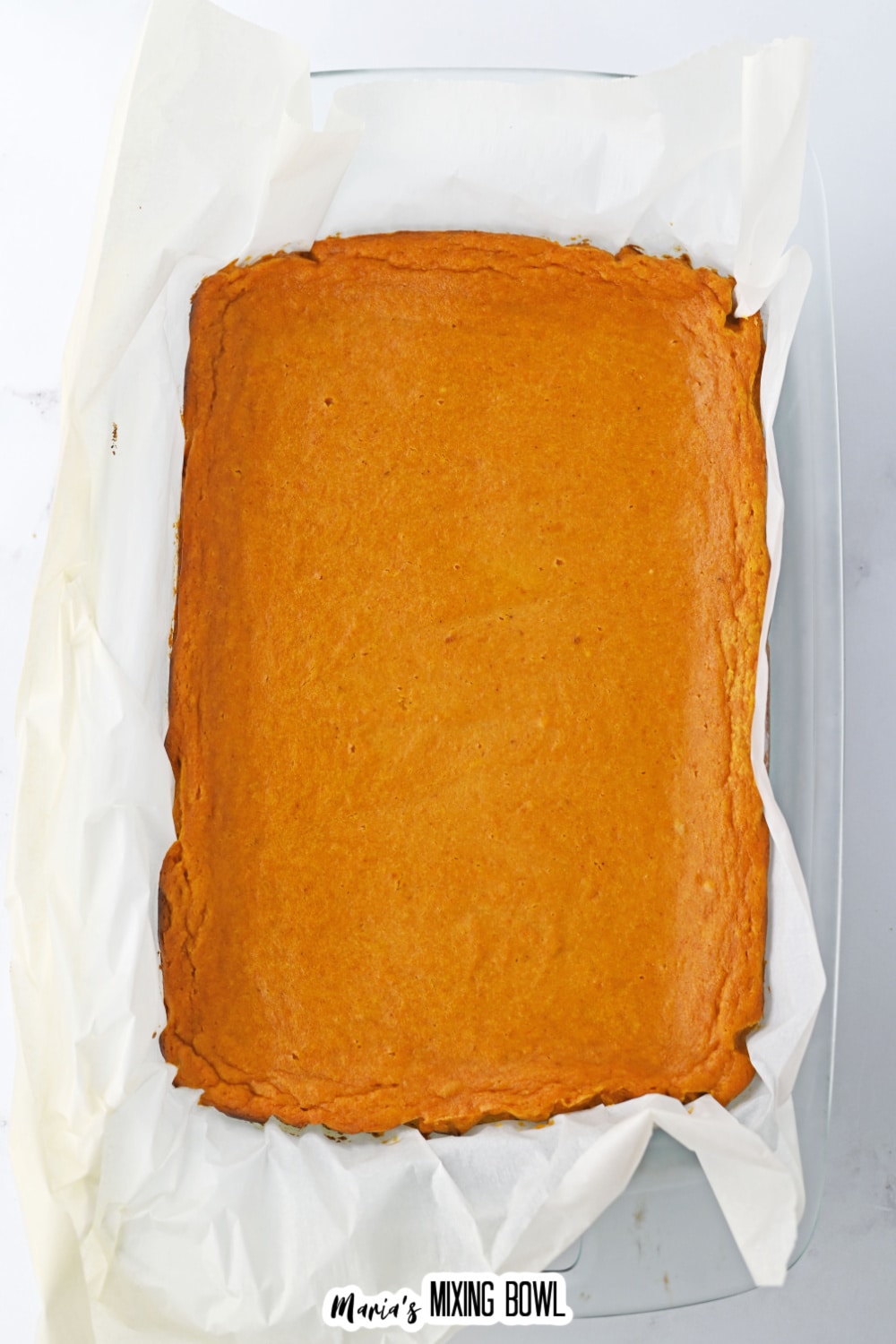 baked pumpkin bars in a parchment lined baking dish.