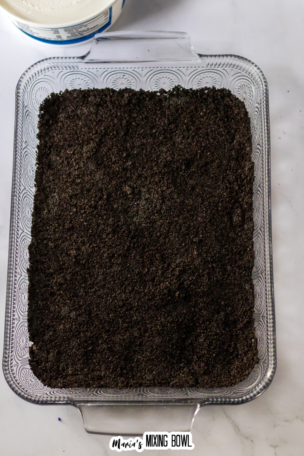 Oreo cookie crush pressed into a glass baking dish.