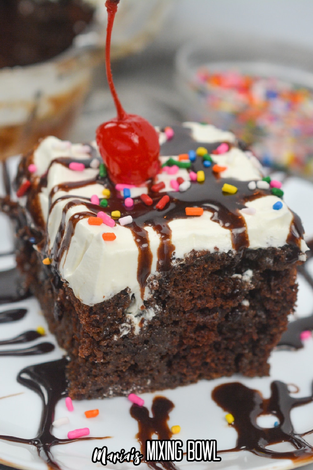 slice of hot fudge poke cake on a plate with a cherry on top.
