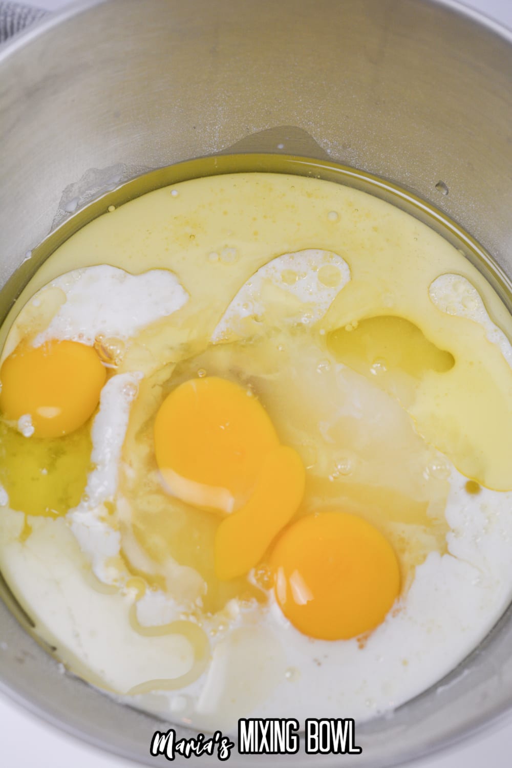 cake batter and raw eggs in a stainless steel mixing bowl.