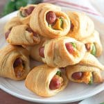 jalapeno crescents pigs in a blanket stacked on top of each other on a plate.