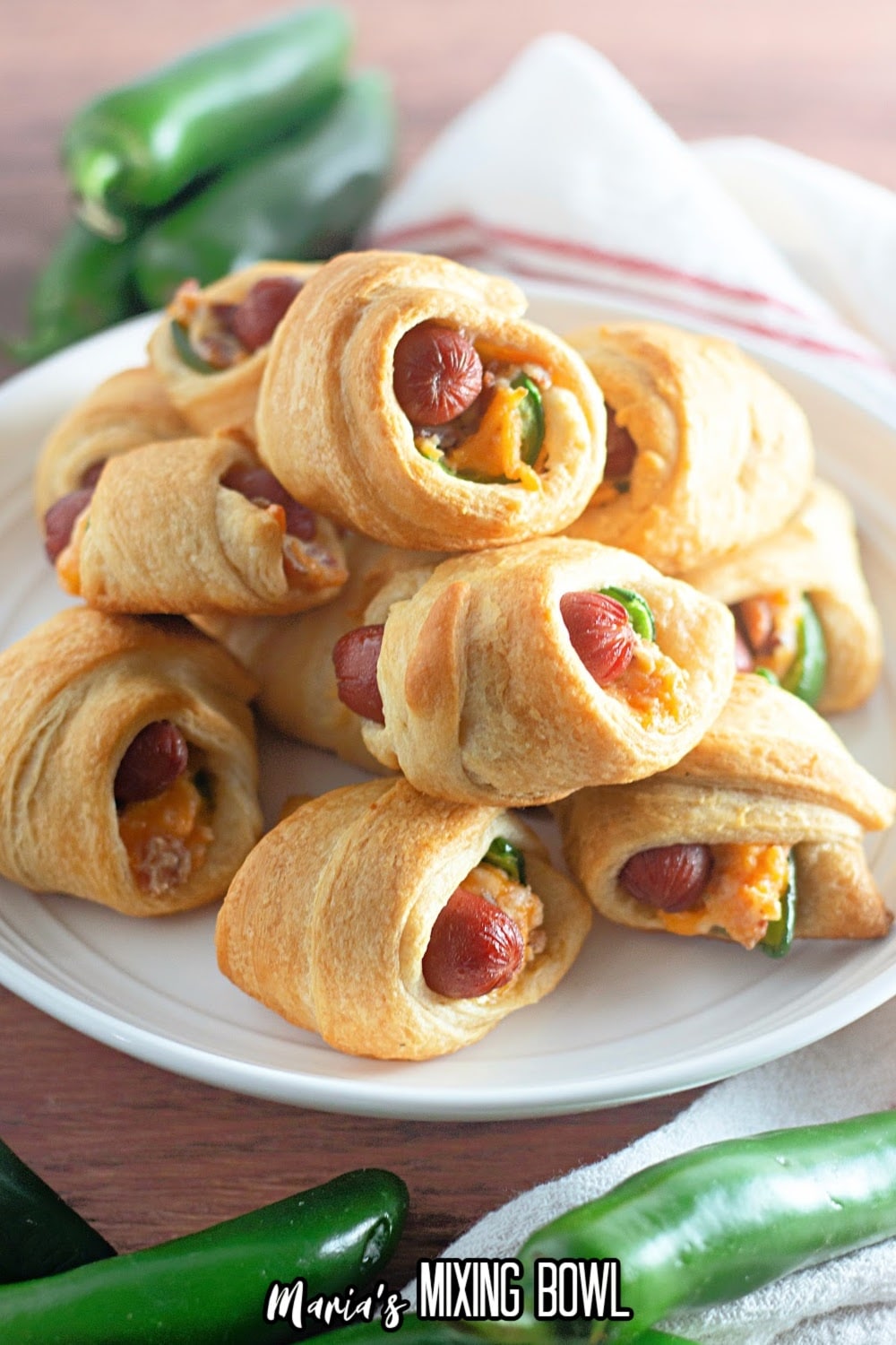 jalapeno crescents pigs in a blanket stacked on top of each other on a plate.