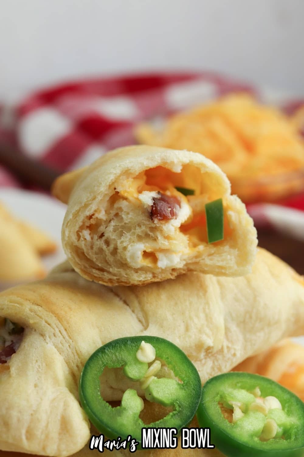 half of a jalapeno popper crescent roll cut open stacked on top of a whole one.