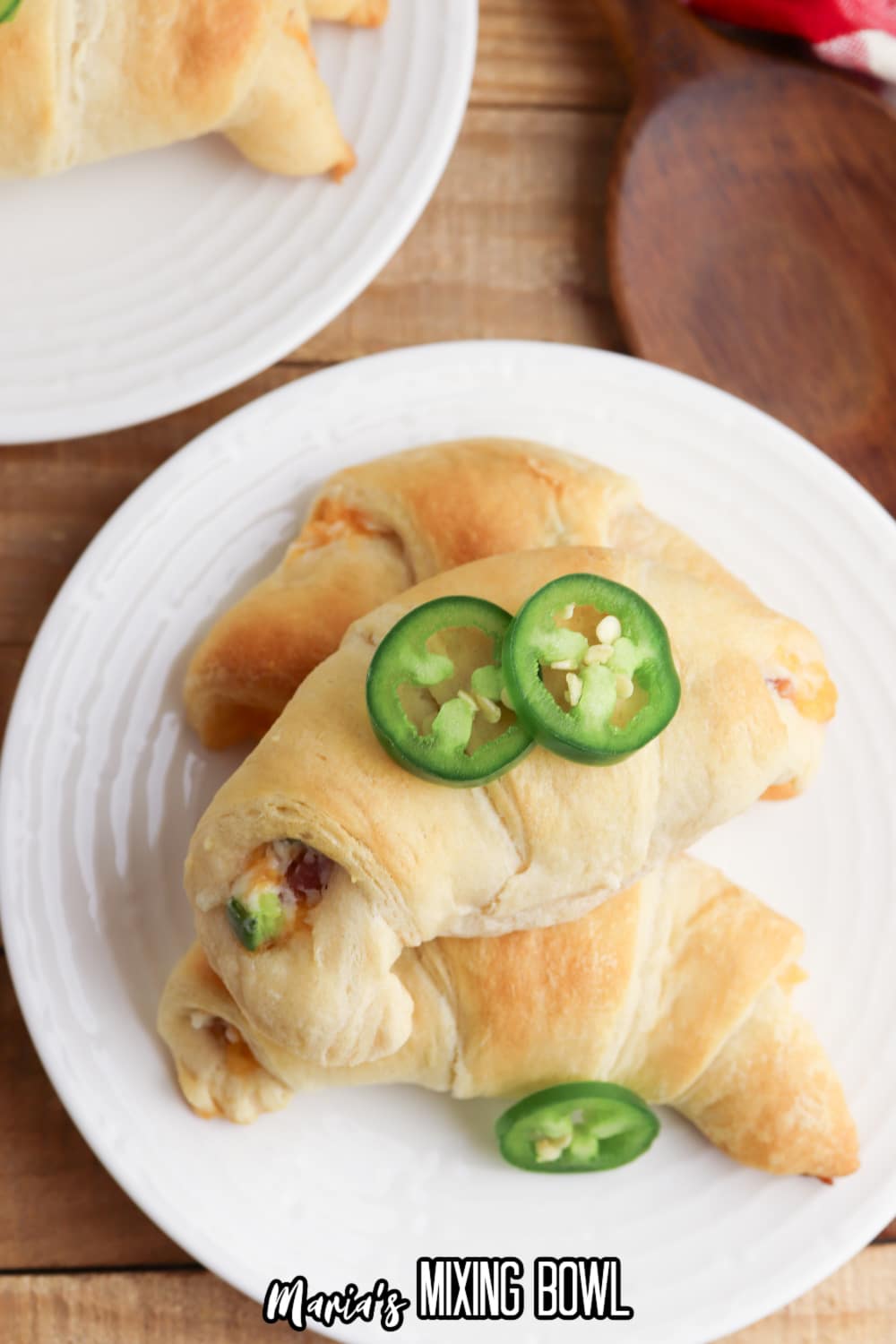 three uncut stuffed crescent rolls on a plate.