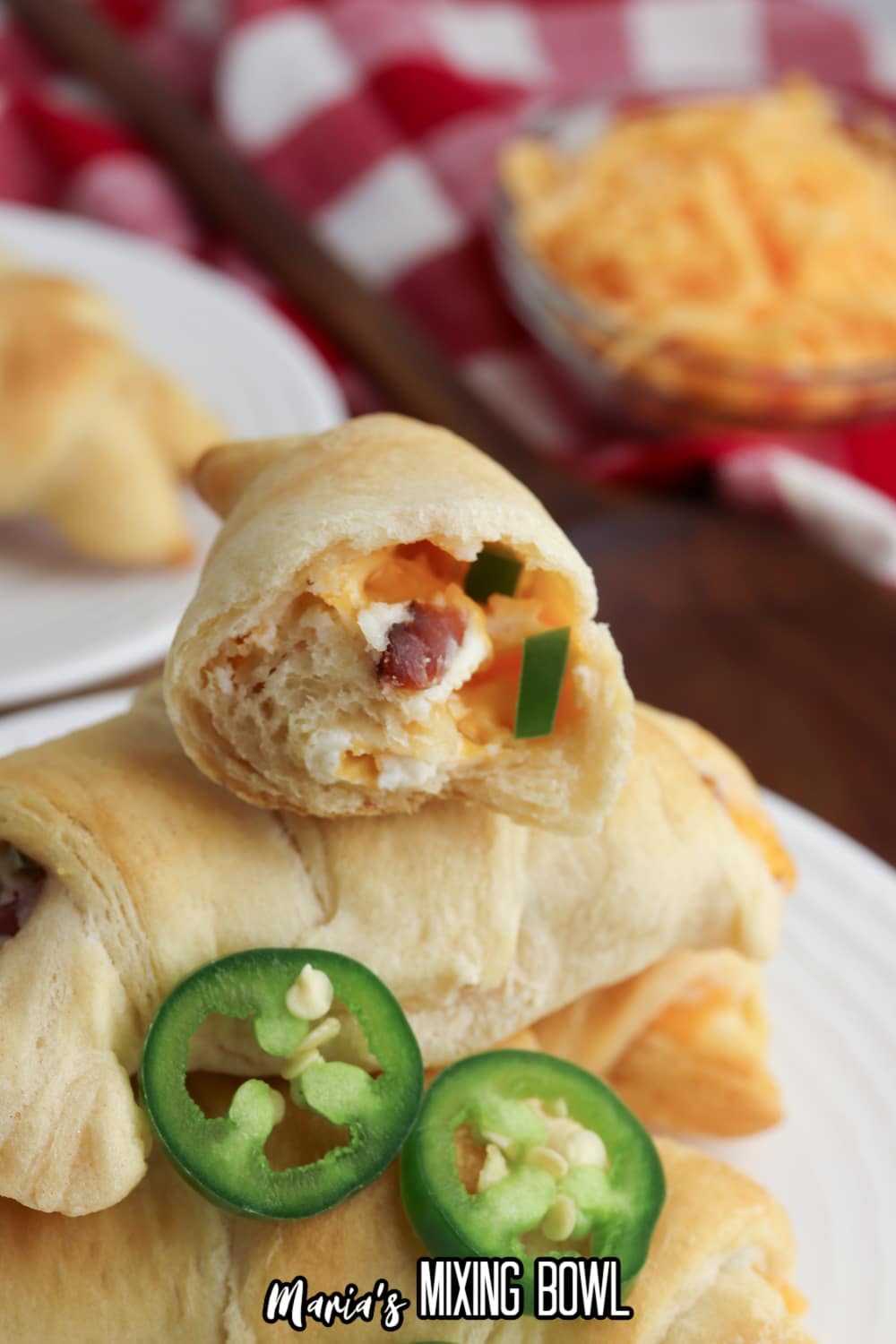half of a jalapeno popper crescent roll cut open stacked on top of a whole one.