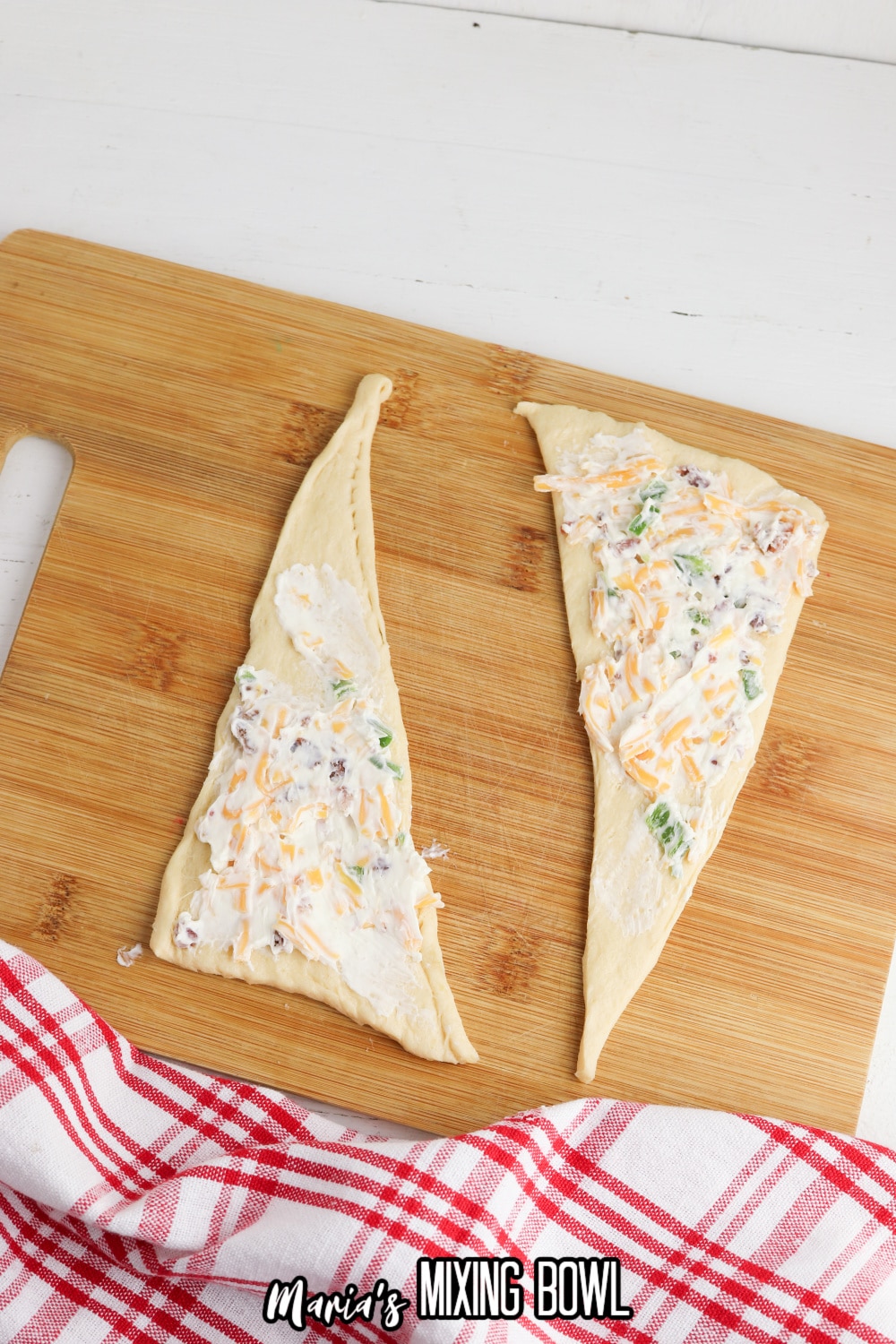 cream cheese filling being spread on raw crescent roll dough.