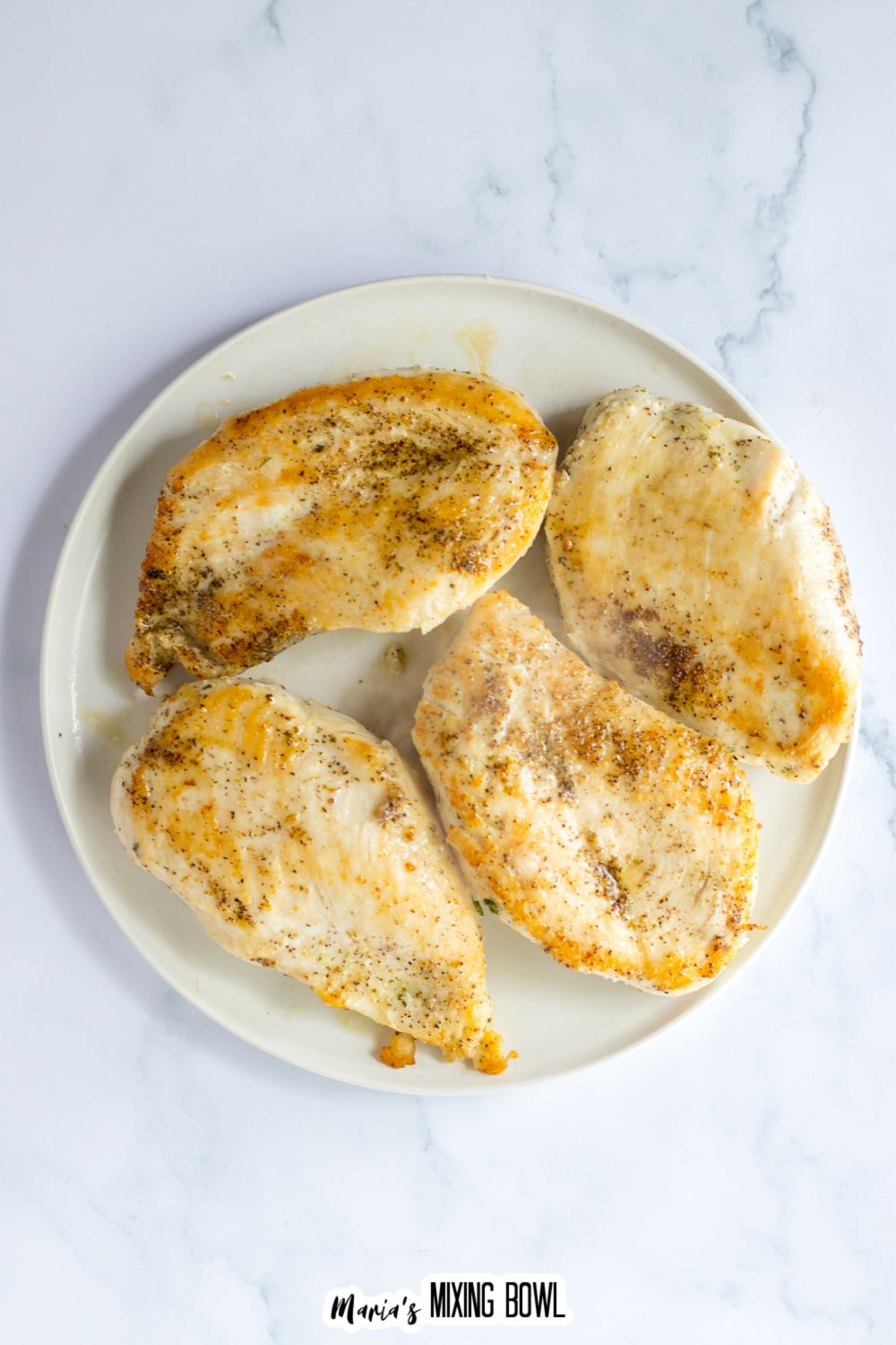 seared chicken breasts on a white plate.