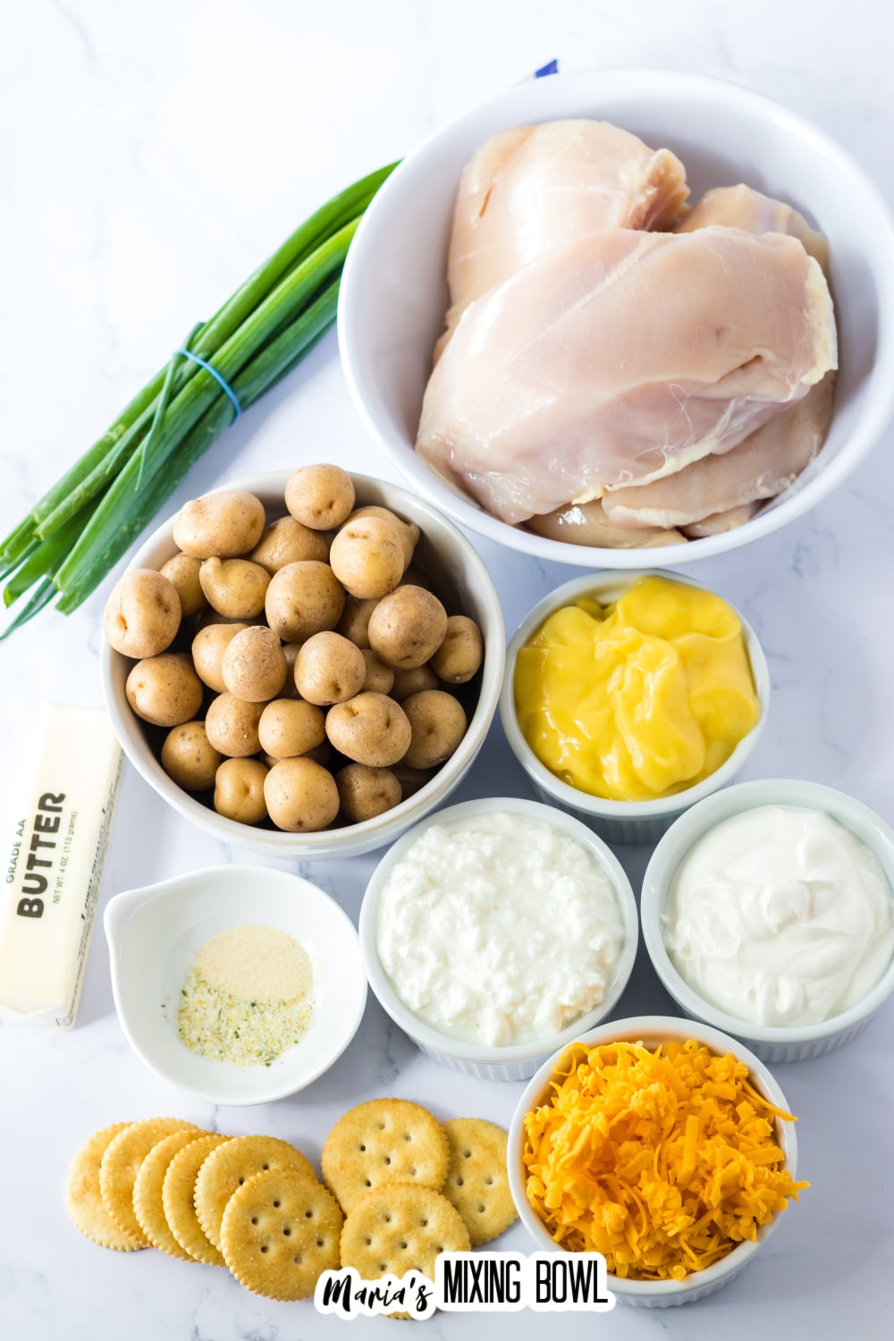 bowls of raw chicken breasts, potatoes, cream of chicken soup, sour cream, cottage cheese, shredded cheese, butter, seasonings, and ritz crackers.