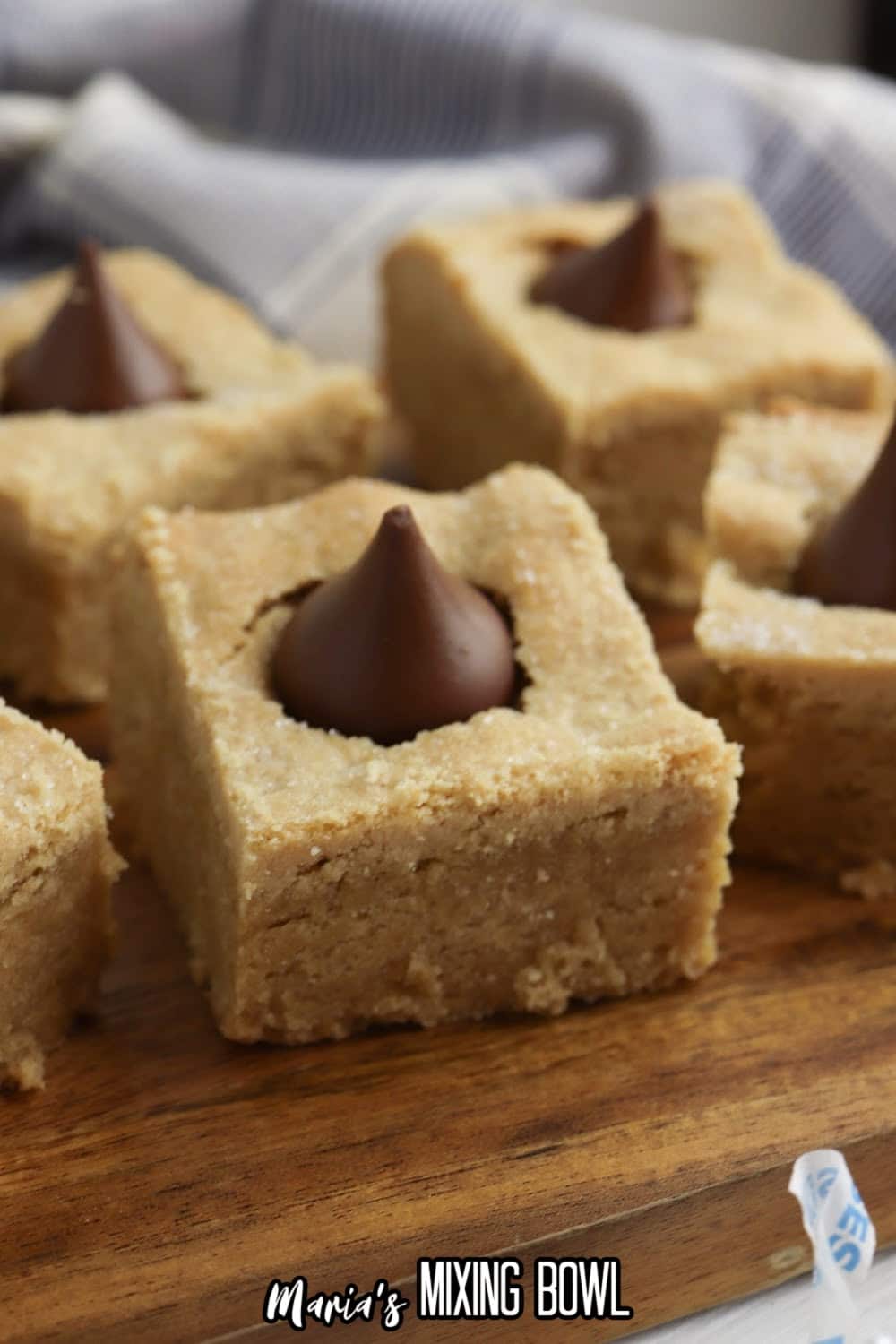 six peanut butter blossom bars on a wooden cutting board.