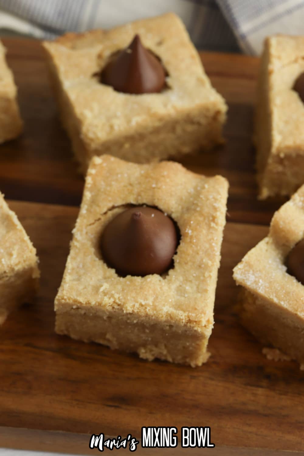 six peanut butter blossom bars on a wooden cutting board.