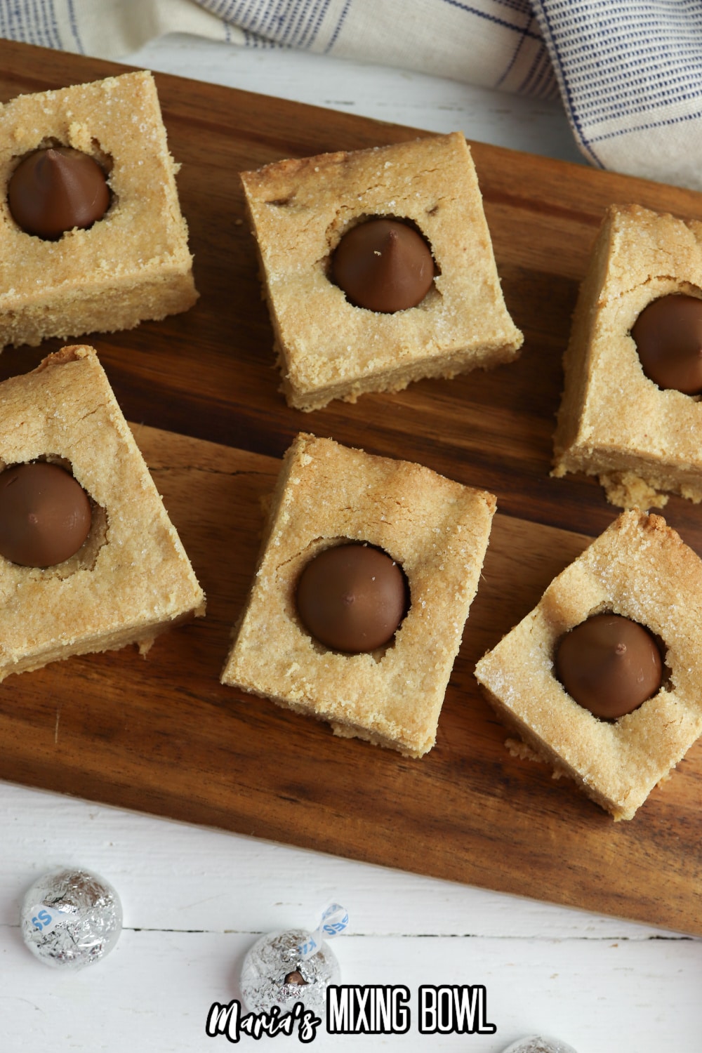 six peanut butter blossom bars on a wooden cutting board.