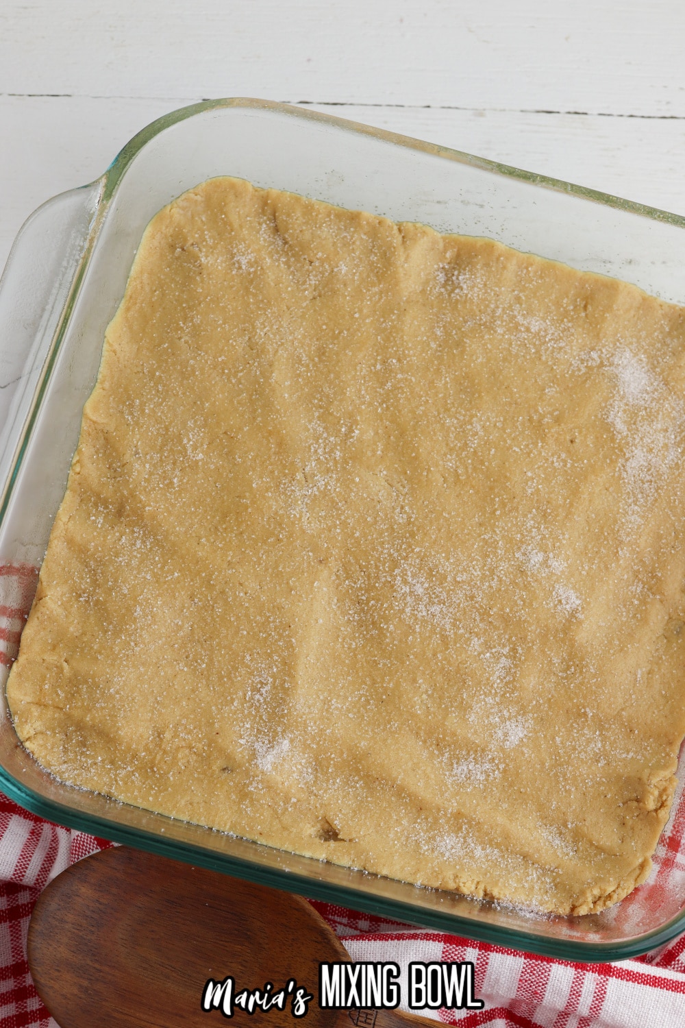 raw peanut butter dough in a glass baking dish sprinkled with sugar.