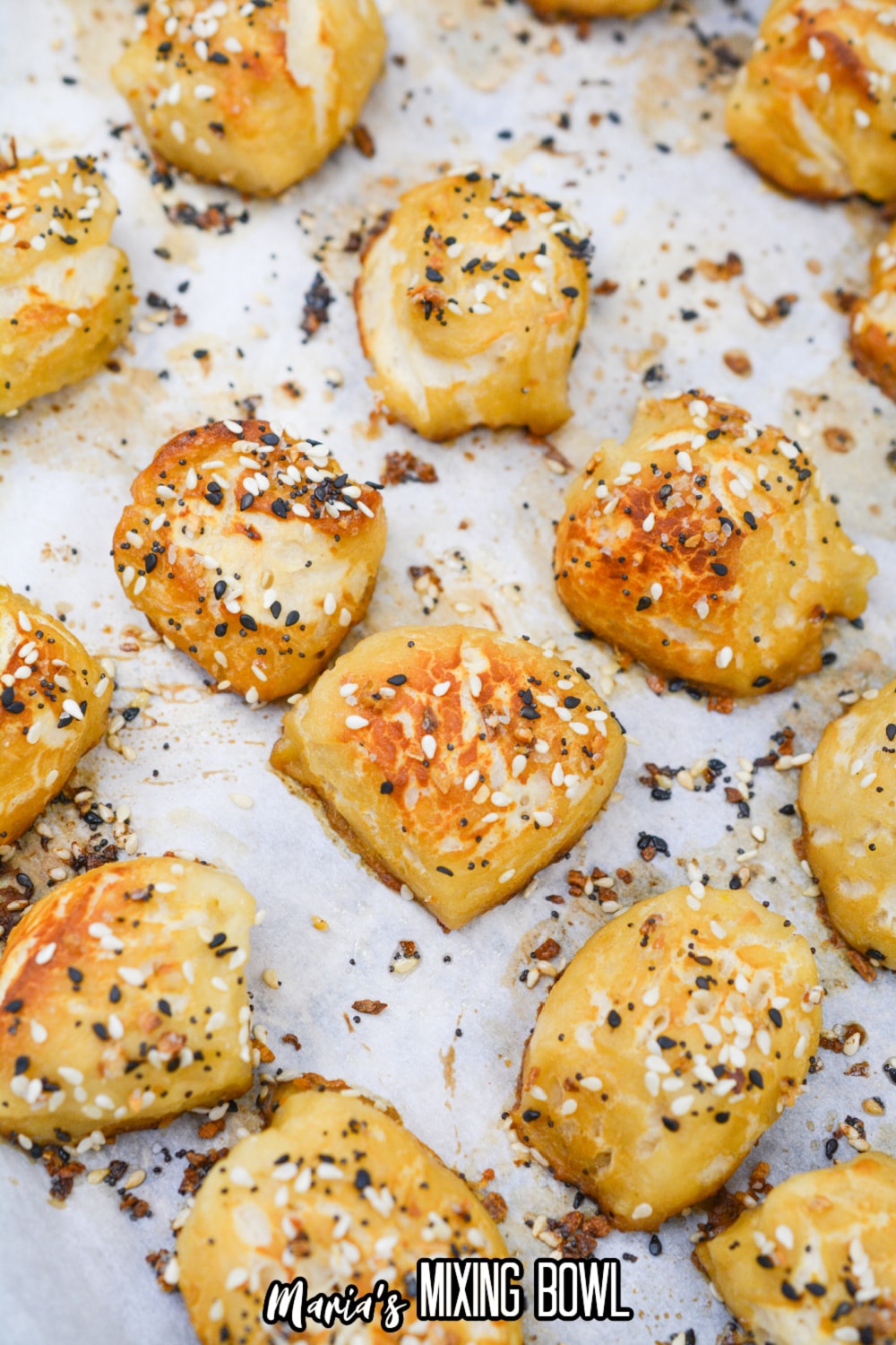 cooked pretzel bites topped with everything bagel seasoning on a parchment lined baking sheet.