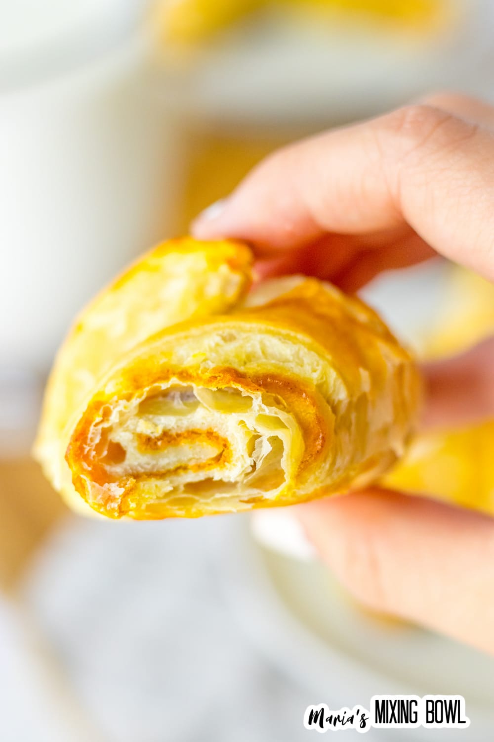 pumpkin pie crescent roll held in the air in a woman's hand.