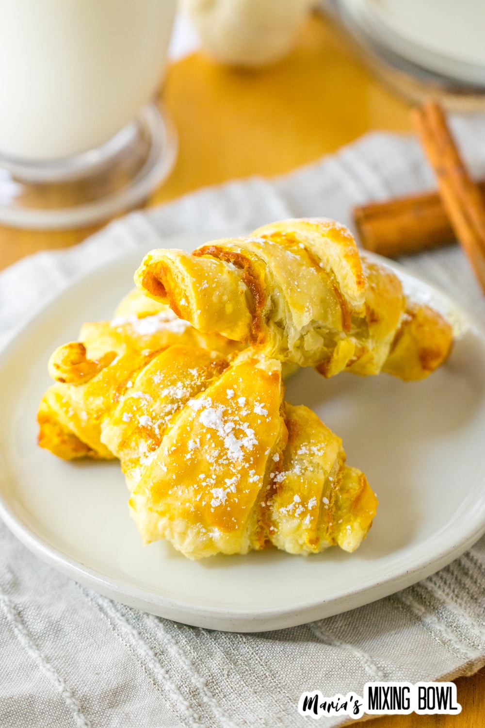 three pumpkin pie crescent rolls stacked on a plate.
